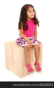 Attractive 3 year old mixed race american girl sitting on wooden block day-dreaming over white background.
