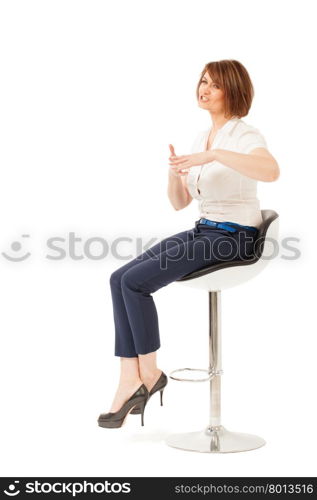 Attractive adult woman on chair talking and showing something with hands. Isolated, studio shot.