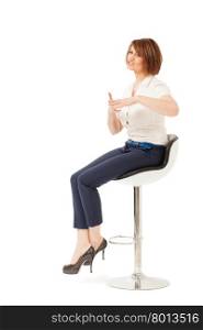 Attractive adult woman on chair talking and showing something with hands. Isolated, studio shot.