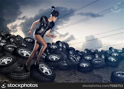 Attractive african woman running on tires on the cloudy sky