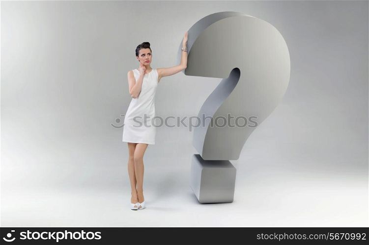 Attractive and astonished woman leaning against the huge question mark