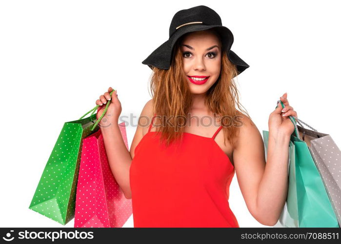 Attractive and young woman in a red dress holds bags in her hands and enjoys shopping.