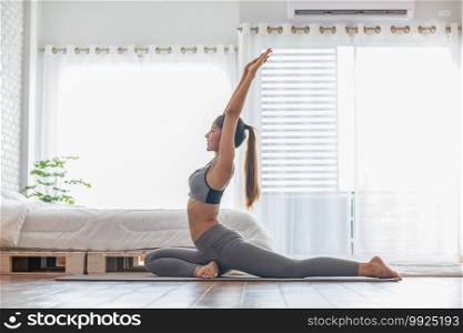 Attractive Asian woman practice yoga pigeon pose to meditation at home in bedroom after wake up in the morning Feeling so comfortable and relax,Yoga for Healthcare Concept