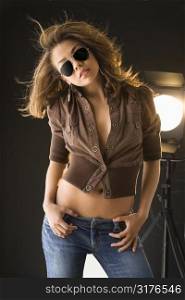Attractive Asian woman wearing sunglasses with studio light in background.