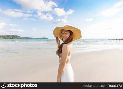 Attractive Asian young woman wearing white dress smile enjoy with summer vacation on the beach feeling so happiness and cheerful,Travel in tropical beach in Thailand,vacations and relaxation Concept