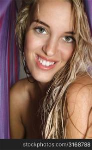 Attractive bare Caucasian woman smiling at viewer with long blond hair.