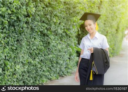 Attractive Beautiful Asian Graduated woman in cap and gown smile with certificated feeling so proud and happiness in success graduated day,Education Success Concept