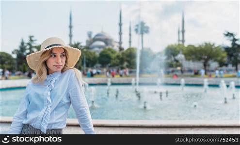 Attractive beautiful girl with a hat poses in front of Sultan Ahmet Mosque in Istanbul,Turkey.Travel Concept