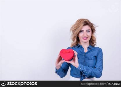 Attractive beautiful model woman holds heart shaped gift box.Valentine&rsquo;s Day concept in studio on a white background.