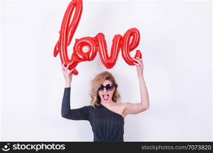 Attractive beautiful model woman holds love word letter shaped red balloon.Valentine&rsquo;s Day concept in studio on a white background.