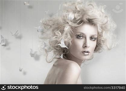 Attractive blond beauty with origami in the background