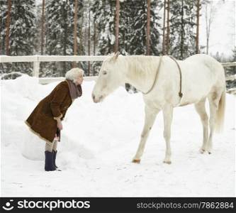 Attractive blond woman and a white horse together, overcast winter day