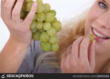 Attractive blond woman eating bunch of grapes