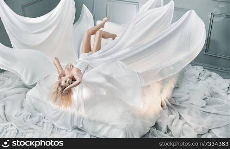 Attractive blond woman lying on pure white sheet