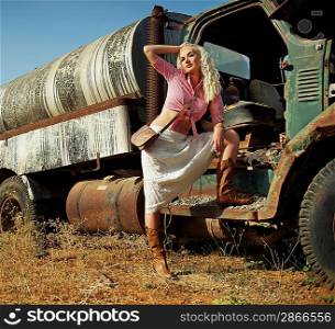 Attractive blond woman near the old car