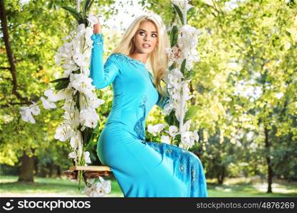 Attractive blond woman on a flower swing in a park