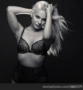 Attractive blond woman wearing black lingerie, black background