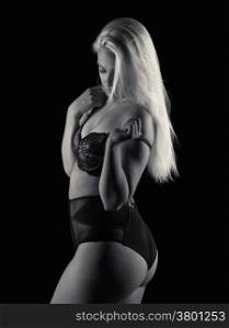 Attractive blond woman wearing black lingerie, black background