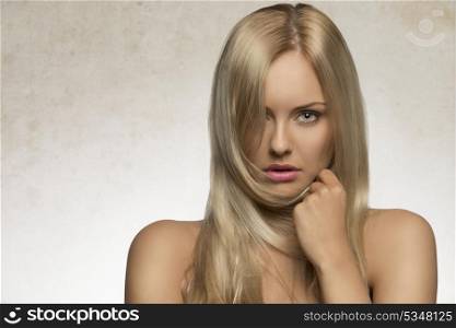 attractive blonde female posing in beauty shoot with perfect skin, naked shoulders and long silky smooth hair