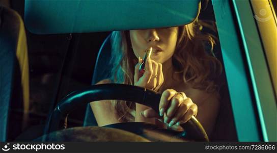 Attractive blonde lady using lipstick in a car