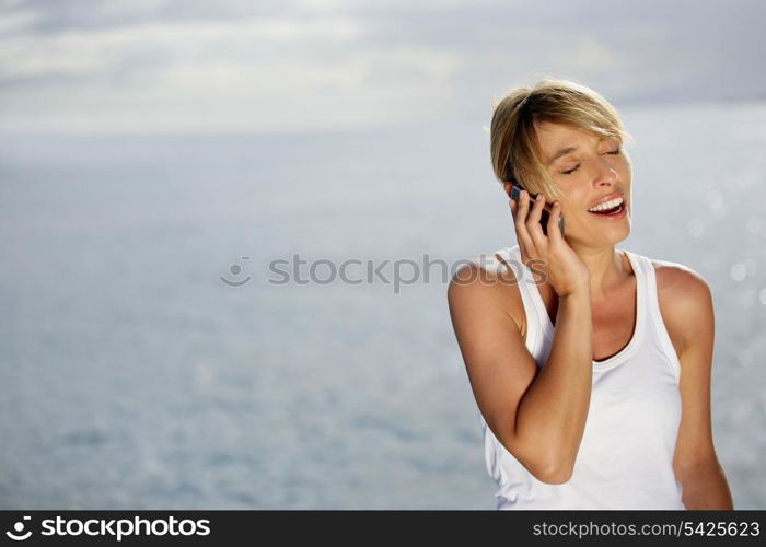 attractive blonde making a call at sunset against sea background