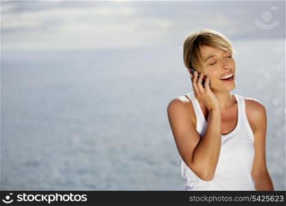 attractive blonde making a call at sunset against sea background