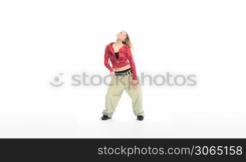 Attractive blonde woman dressed in baggy pants and blouse doing a modern dance, studio on white