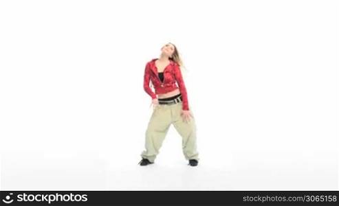 Attractive blonde woman dressed in baggy pants and blouse doing a modern dance, studio on white
