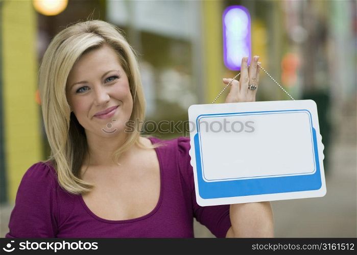 Attractive blonde woman holding a blank sign