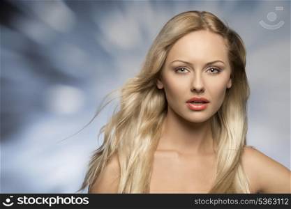 attractive blonde woman in close-up portrait posing with long flying silky hair and perfect skin. Looking in camera