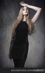 attractive blonde woman in fashion pose with Halloween style, long blonde hair, dark make-up and sexy gothic clothes