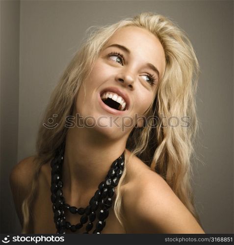 Attractive blonde woman looking to side wearing beaded necklace.