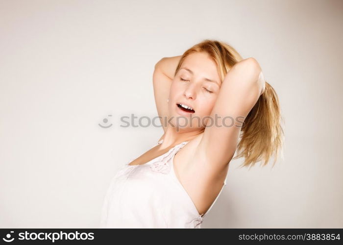 Attractive blonde woman with no make up yawning stretching waking up gray background