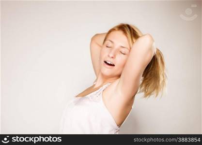 Attractive blonde woman with no make up yawning stretching waking up gray background