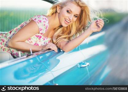 Attractive blonde womanl riding the blue cadillac
