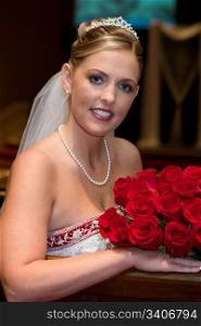 Attractive Bride with a bouquet of roses poses for photographs shortly before the wedding ceremony.