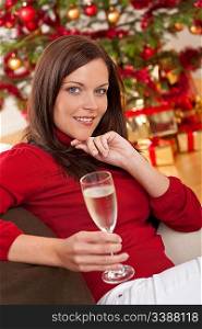 Attractive brown hair woman in front of Christmas tree with glass of champagne