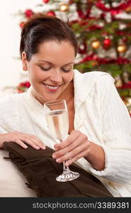 Attractive brown hair woman in front of Christmas tree with glass of champagne