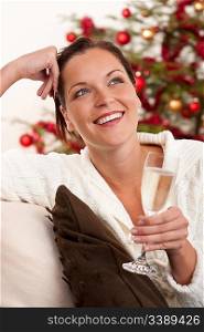 Attractive brown hair woman in front of Christmas tree with glass of champagne