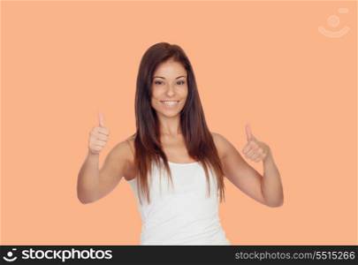 Attractive brunette girl dressed in white saying Ok isolated on a orange background