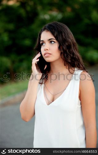 Attractive brunette girl with mobile on the park