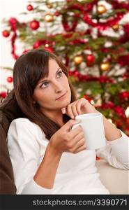 Attractive brunette in front of Christmas tree holding cup of coffee