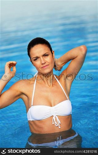 Attractive brunette in swimming pool scratching neck