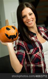 Attractive brunette woman at home with a halloween pumpkin