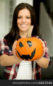 Attractive brunette woman at home with a halloween pumpkin. Selective focus