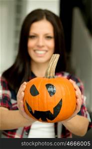Attractive brunette woman at home with a halloween pumpkin. Selective focus