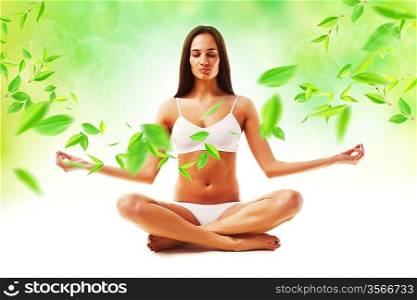 attractive brunette woman in yoga pose and leaves