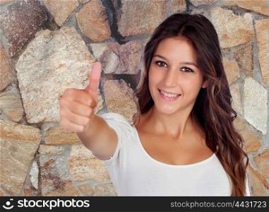 Attractive brunette woman saying Ok with a stone wall of background