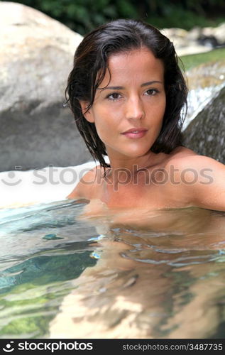 Attractive brunette woman taking a bath in river