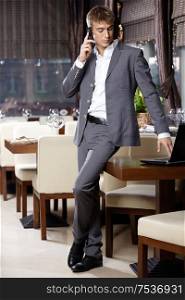 Attractive business man speaks by a mobile phone at restaurant